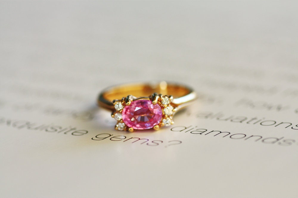 This Rose gold ring is delicately adorned with a Pink Sapphire, showcasing a 3 round brilliant cut diamonds on either side of the gemstone. An elegant and classy union of precious metals and stones.