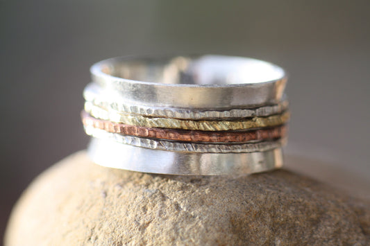 The main band is made of sterling silver with a sterling silver stamp guarantee, while the spinners are composed of copper and brass layers. Measuring approximately 10mm wide and 1mm thick